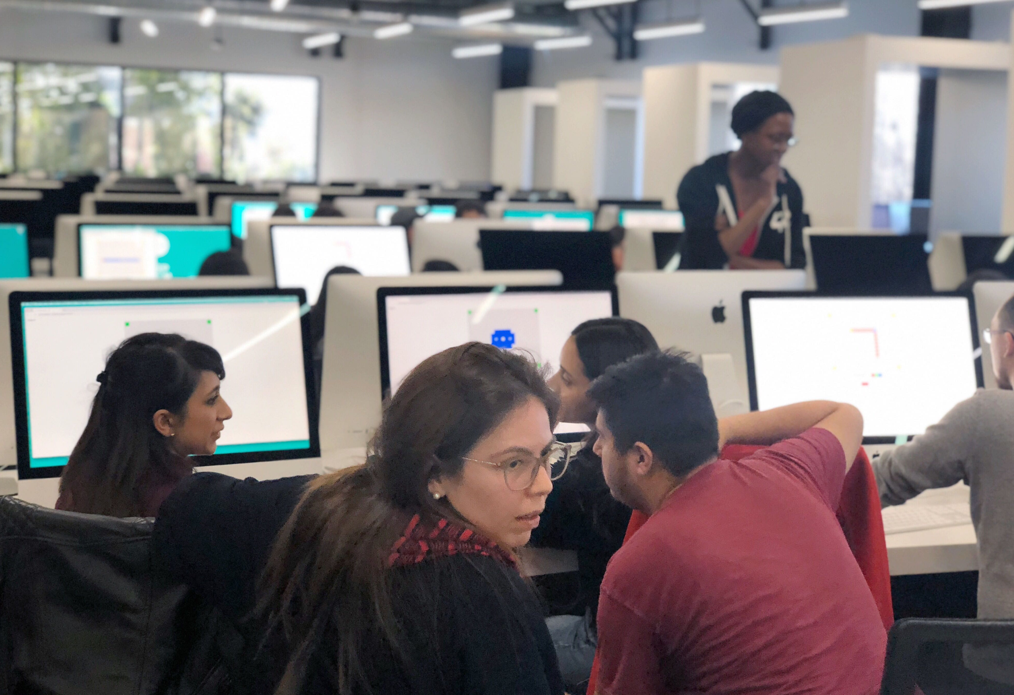 Be polite, social and study hard! A group of students crowding around a copmuter and collaborating.